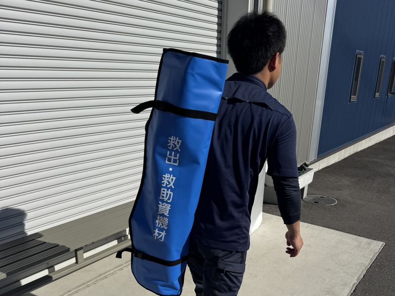 救出・救助資機材バッグを背負って移動する社員